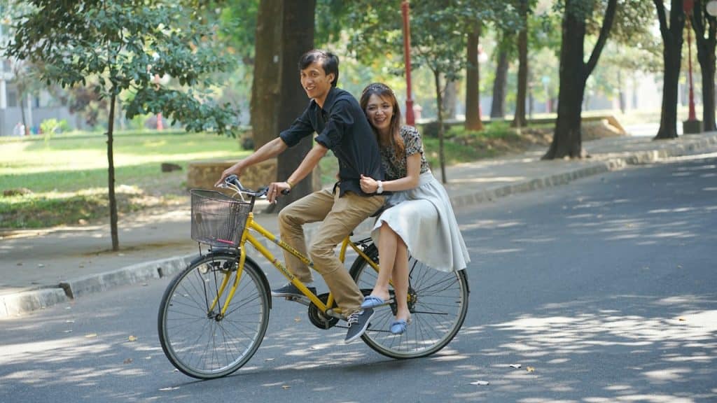 A man and a woman riding a bike down a street.