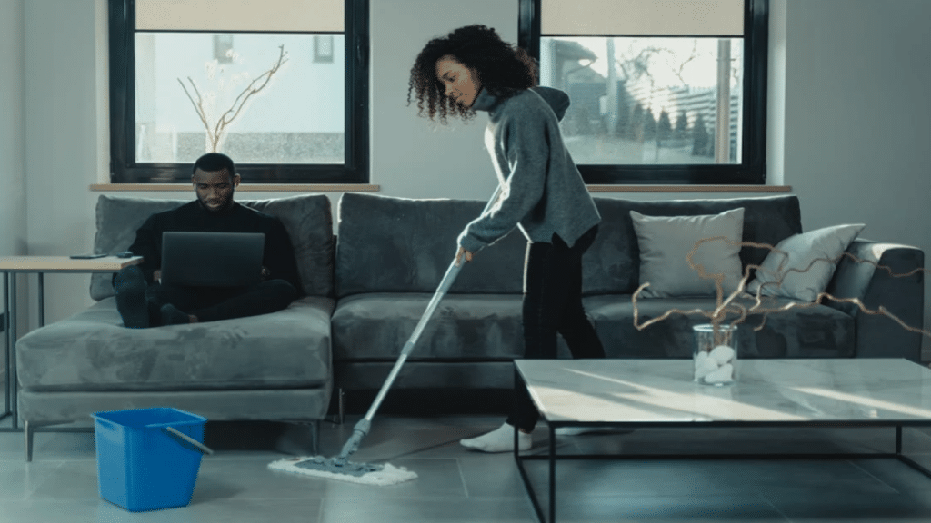 A woman mopping while her husband works
