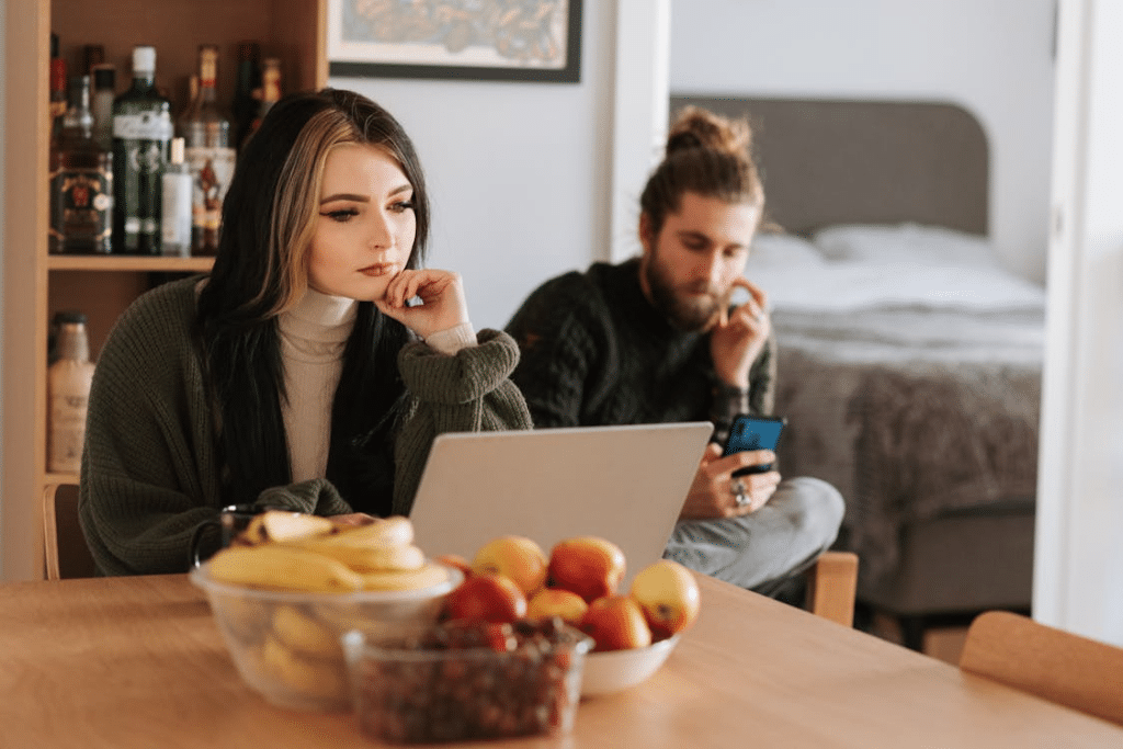 Couple surfing internet on laptop and smartphone in house