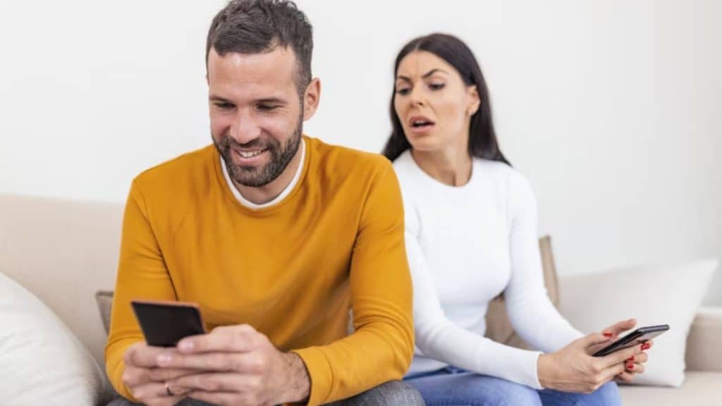 Woman on a couch, man on phone beside her