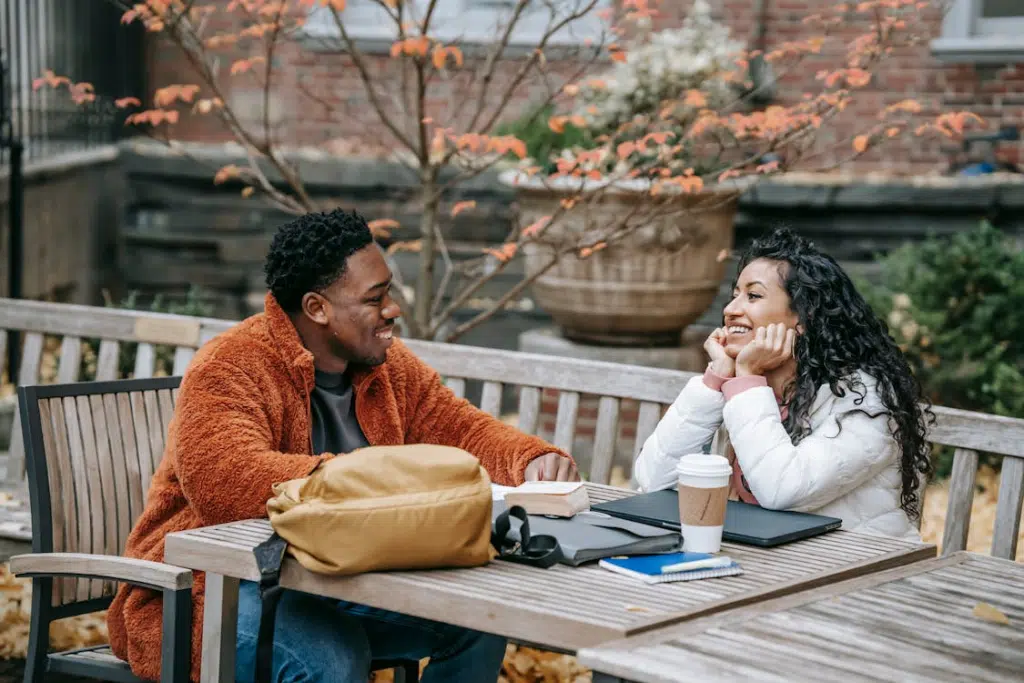 Cheerful multiethnic couple talking and smiling at table