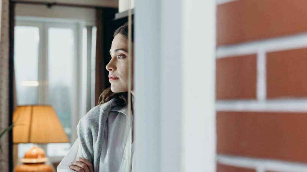 A woman looking out a window indoors.