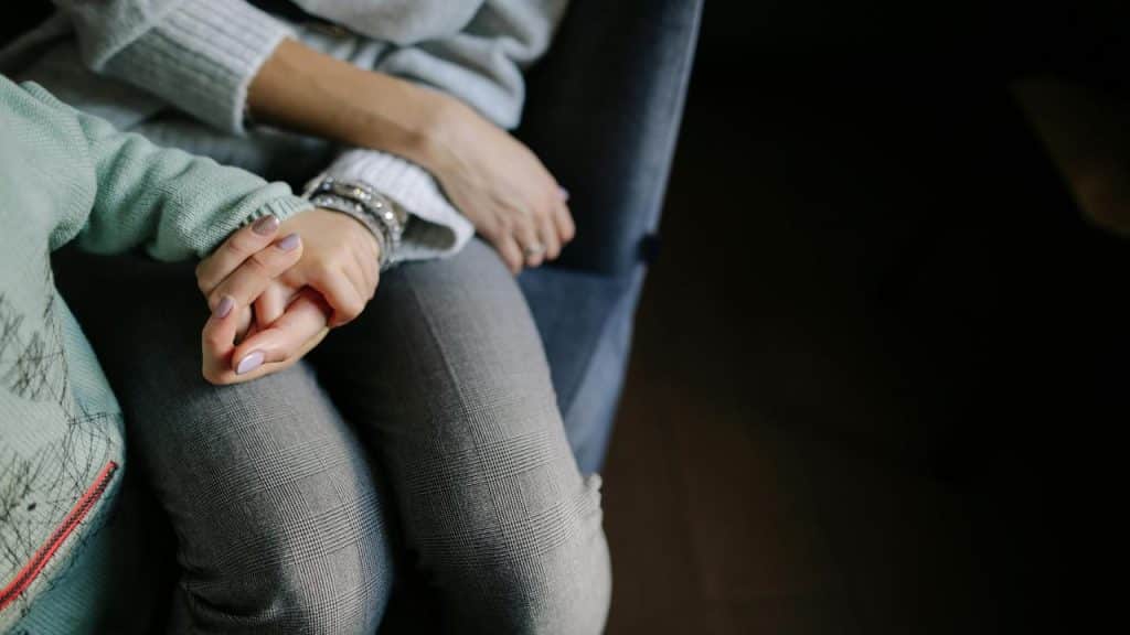 A woman holding a child’s hand while sitting together.