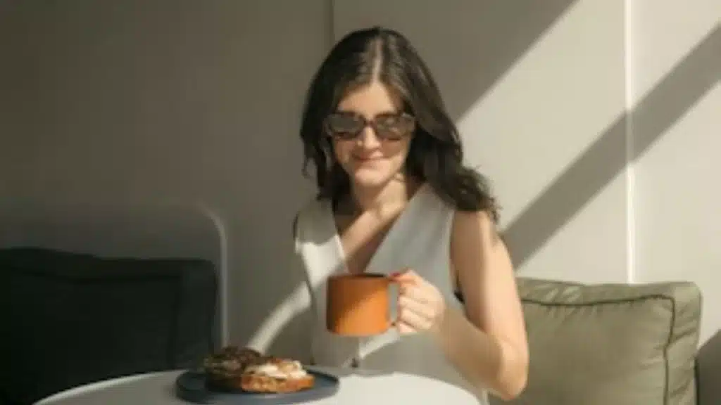 Woman enjoying coffee alone while smiling faintly