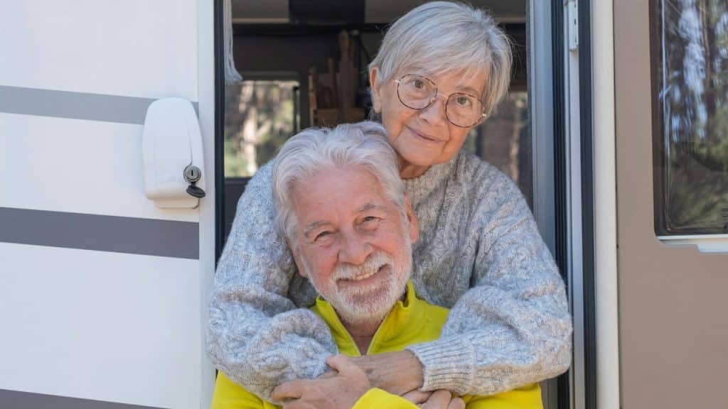 Relaxed senior couple at the door of their camper van.