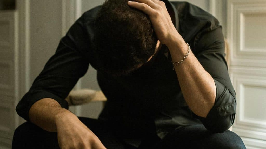 A man sitting with his head in his hand looking stressed.