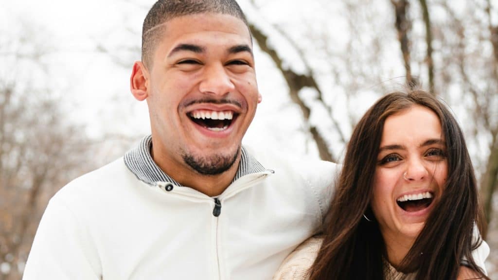 A man and a woman laughing in the snow.