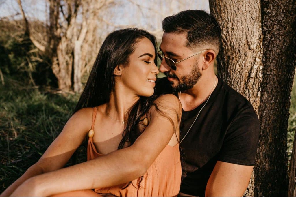 A man and woman leaning at the brown tree