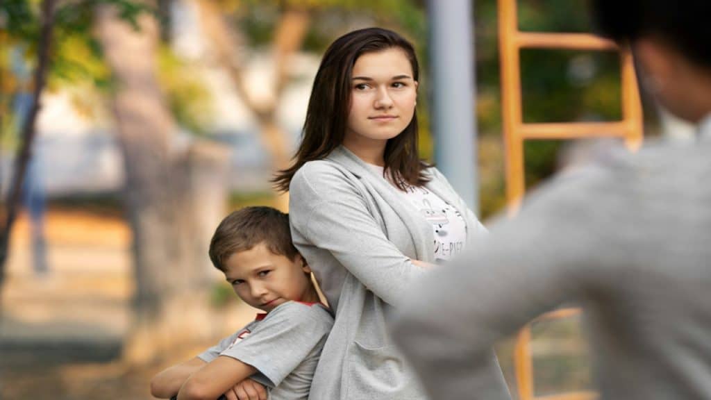 A woman standing back-to-back with her son.