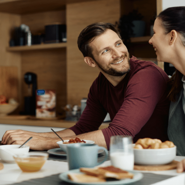 A couple smiling at each other in the kitchen