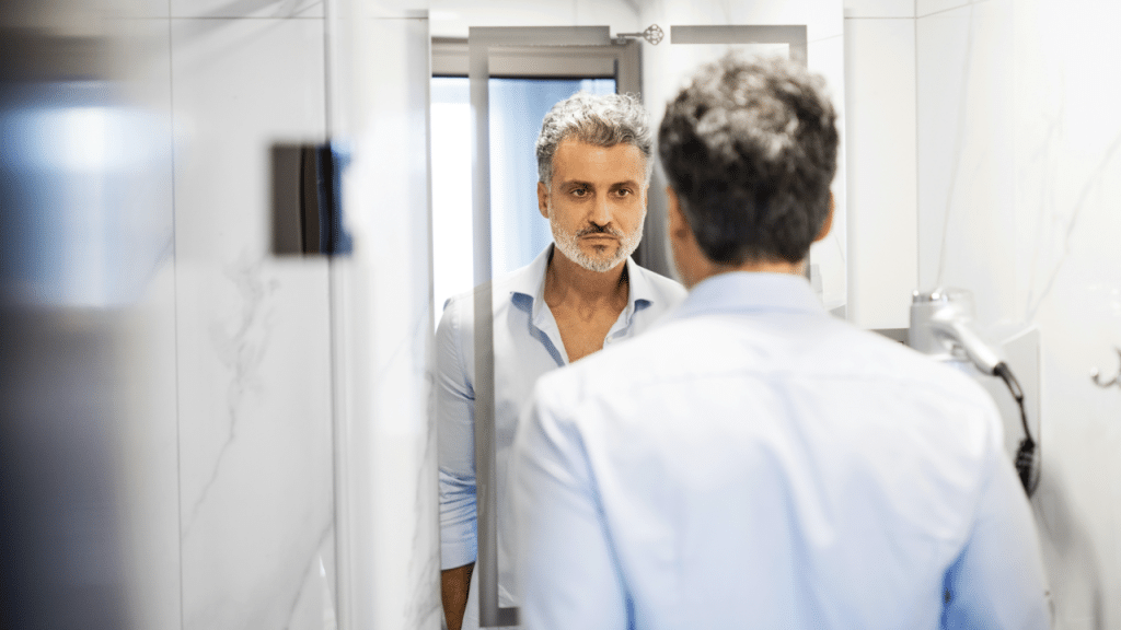 A man looking sadly at a mirror