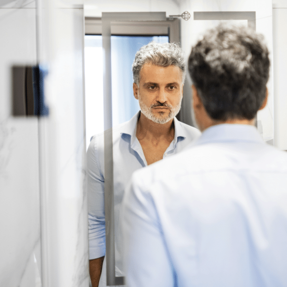 A man looking sadly at a mirror
