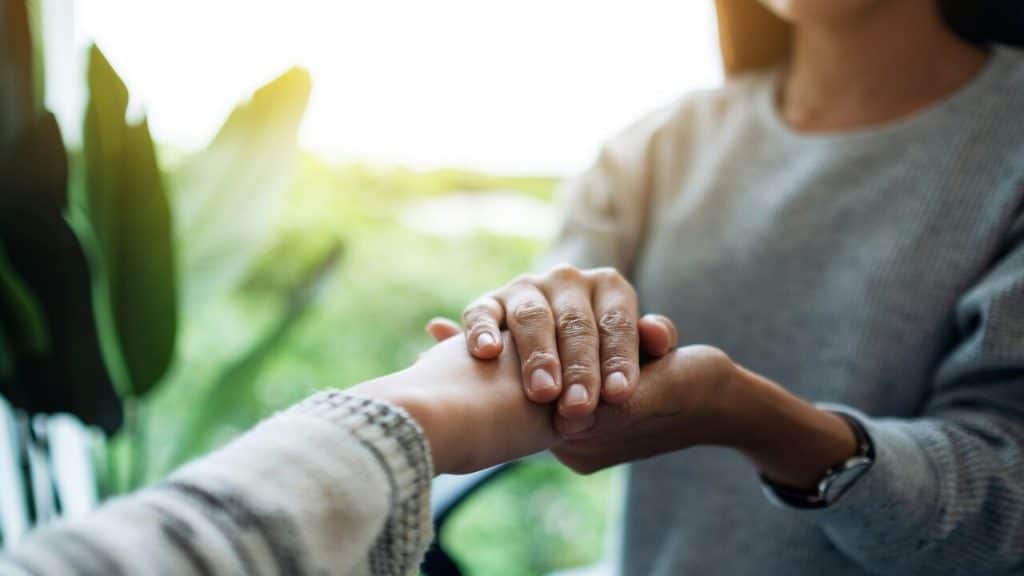 A woman holding her husband’s hand