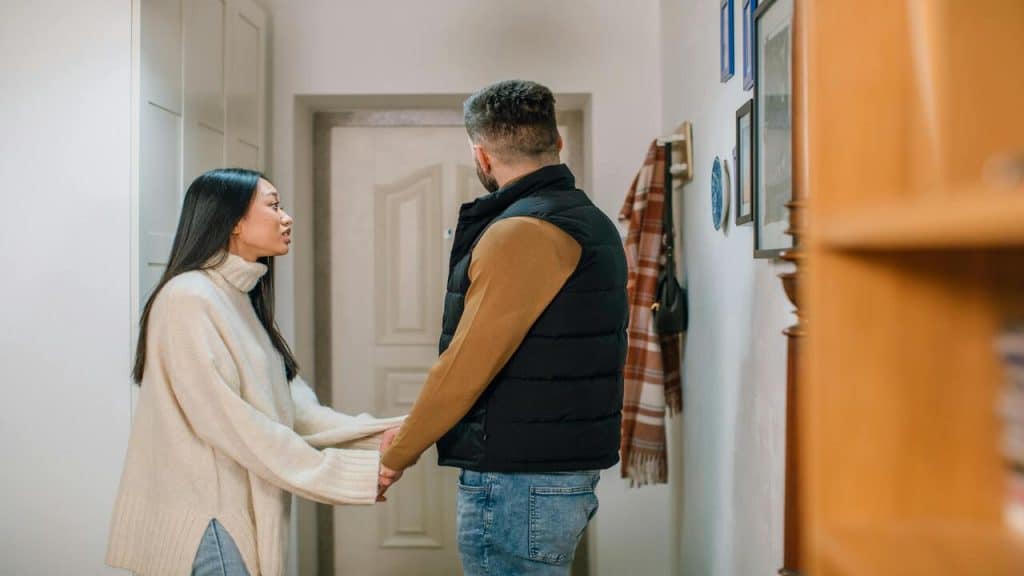 A woman stopping her husband from leaving