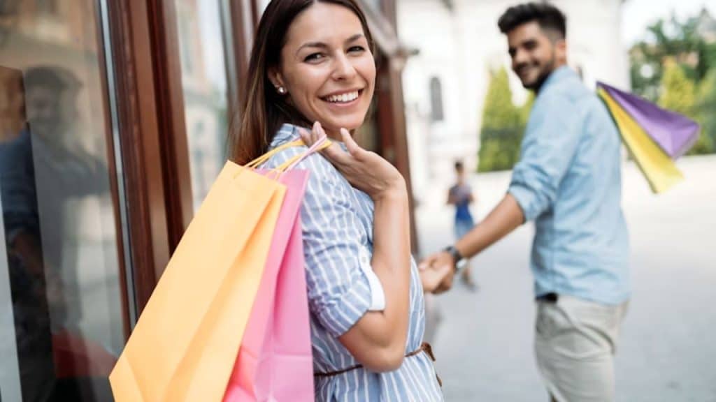 Man and woman carrying holiday shopping bags looking thoughtful