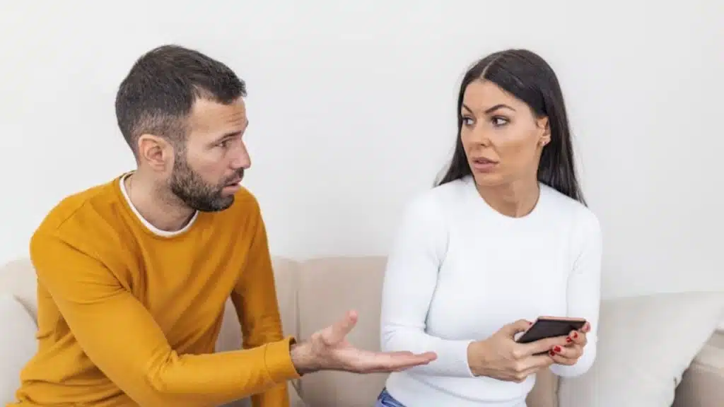 Woman sitting calmly while her partner speaks defensively