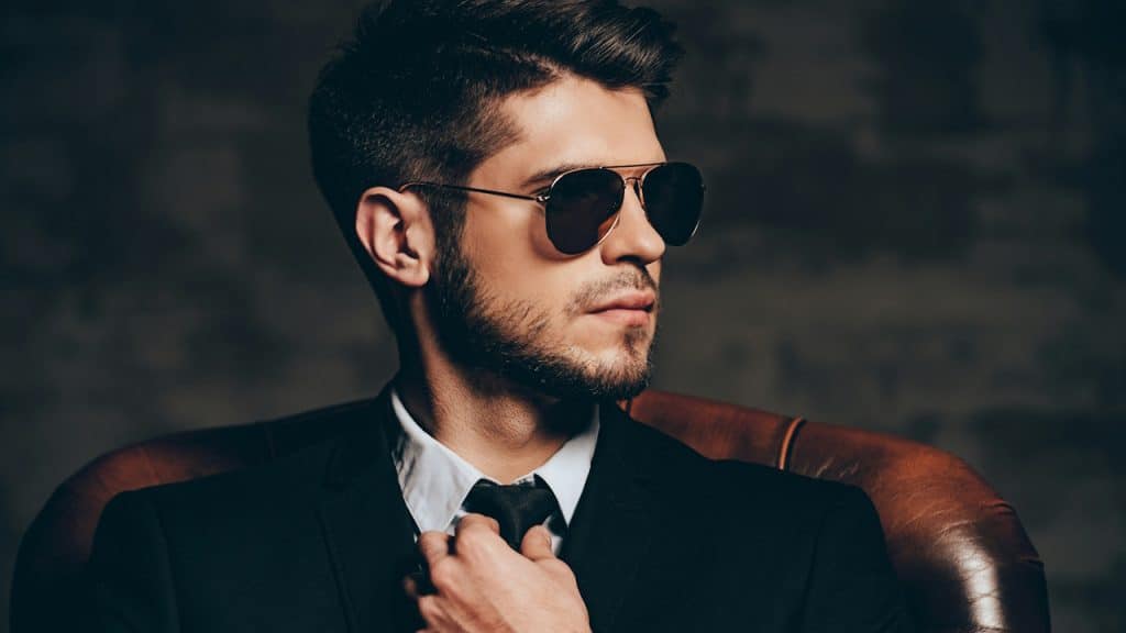A confident man in a suit and wearing sunglasses.