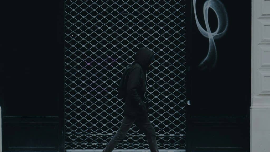 A man walking down a street past a building.