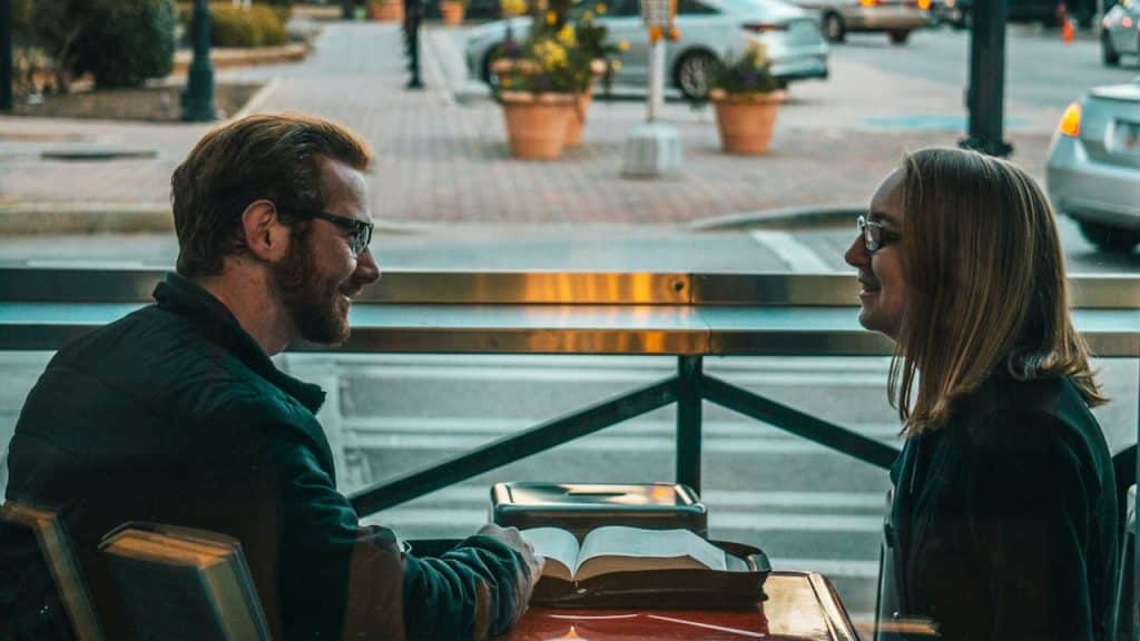 A man and woman sitting while talking during daytime.