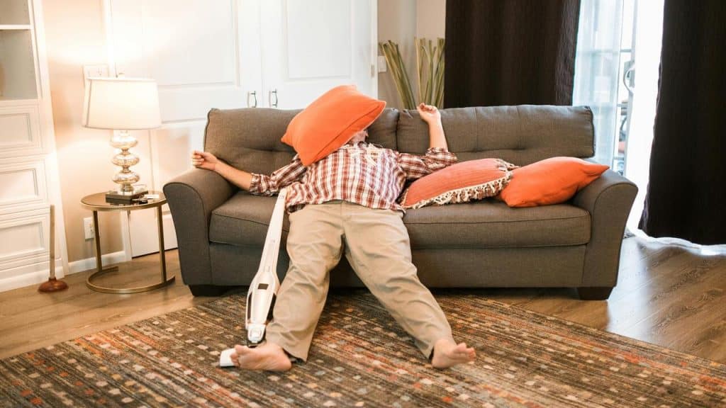 A man sleeping on the couch instead of cleaning 