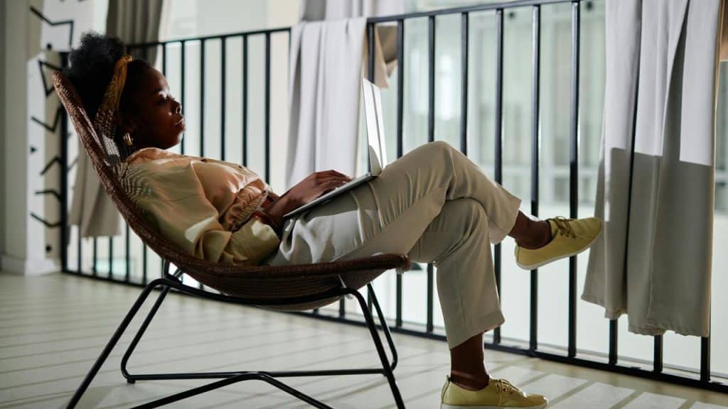 A woman sitting in a chair with a laptop on her lap.