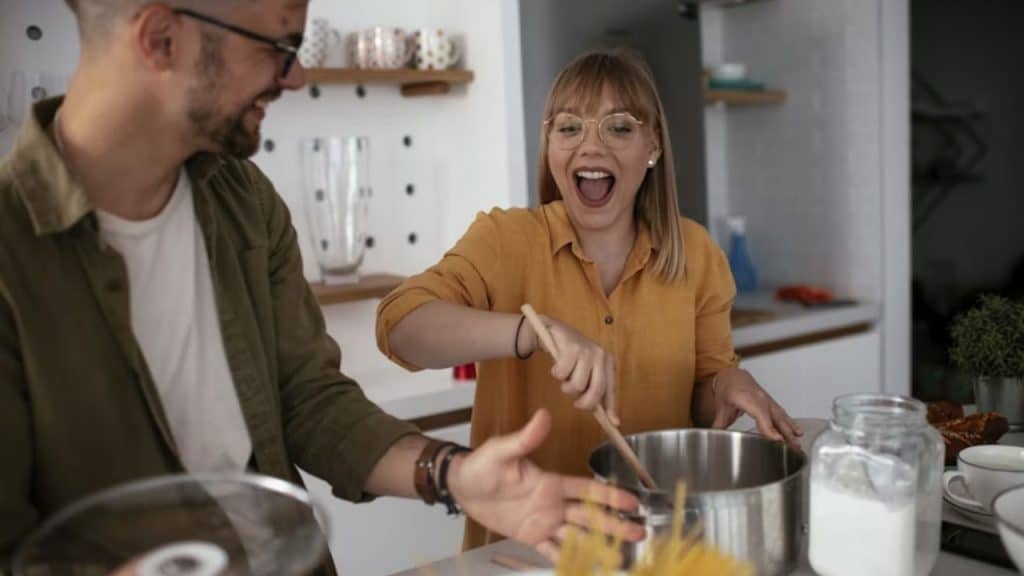 Couple cooking together in a cozy kitchen, laughing