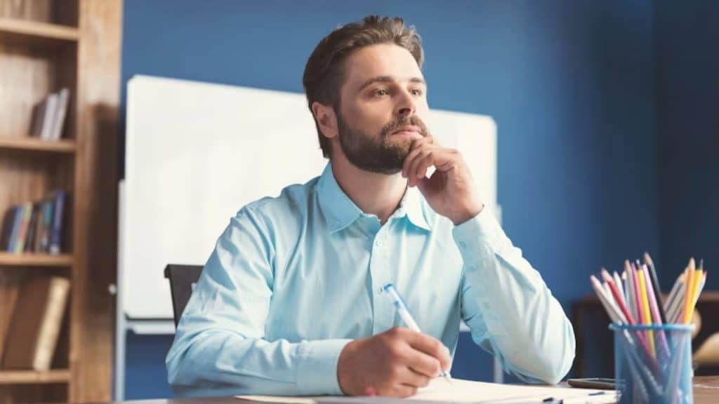 Man sitting at a desk reflecting on decisions with determination