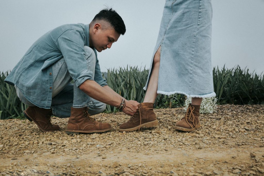 The man is tying the woman’s shoelaces.