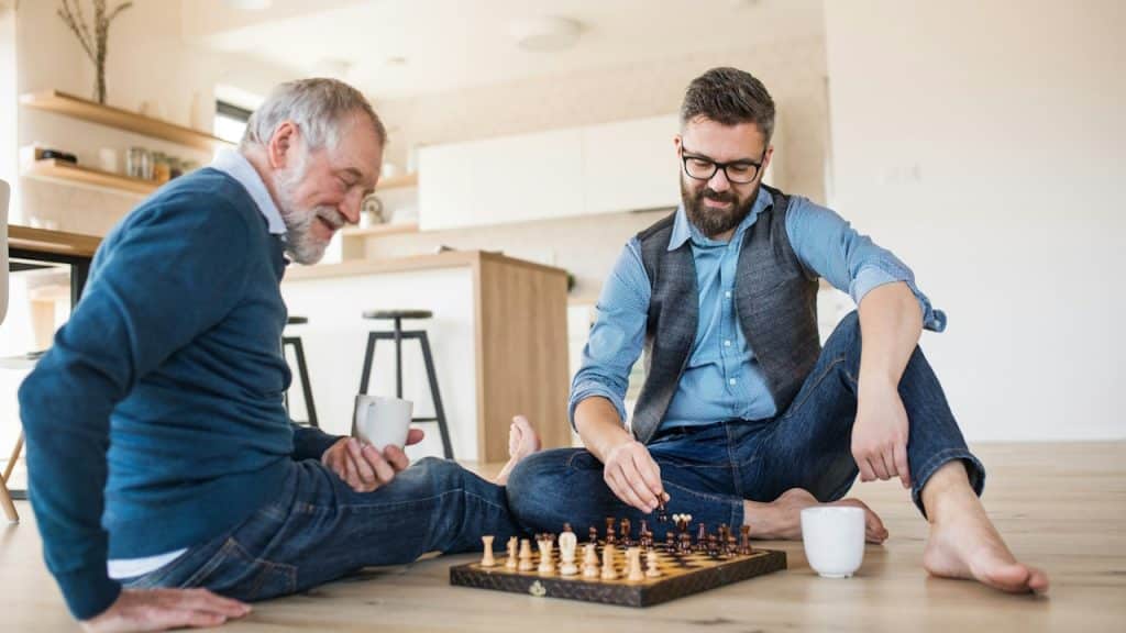 A cheerful son and father playing chess at home.