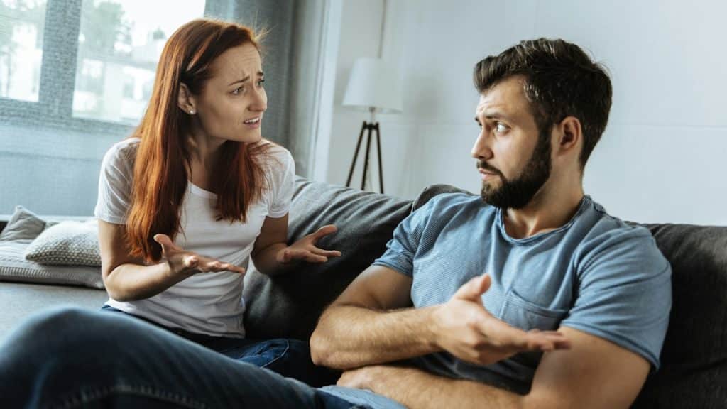 A woman complaining to her indifferent partner while they are seated on a couch.