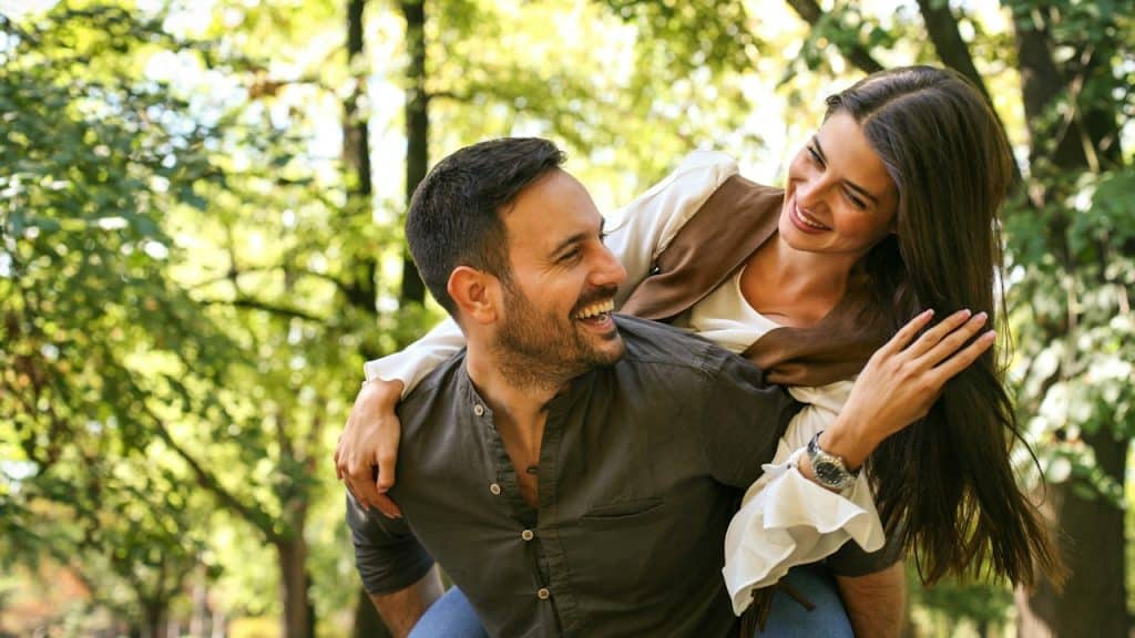 A happy man giving his woman a piggyback ride. 