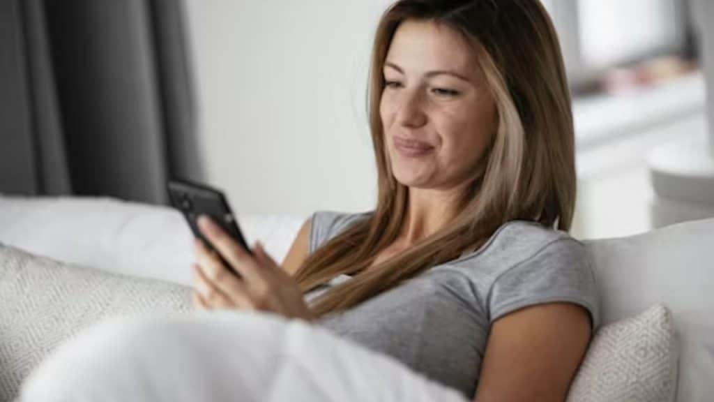 Woman smiling faintly while looking at an old photo on her phone