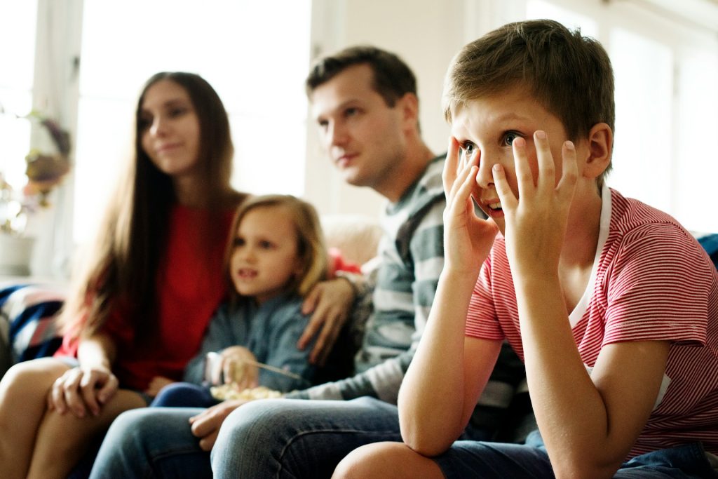A family of four watching television together.