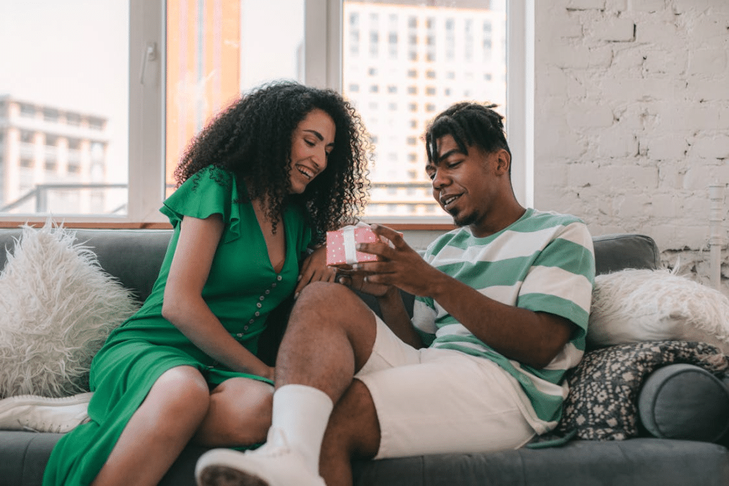 A Couple Sitting on the Sofa while Looking a Gift