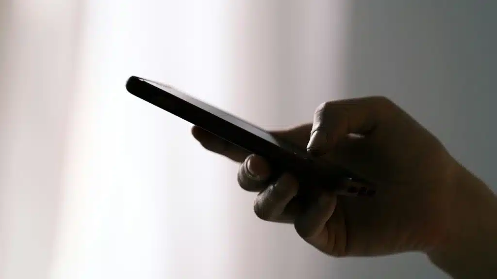 A person holding a smartphone in a dimly lit setting.