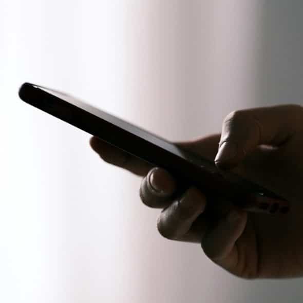 A person holding a smartphone in a dimly lit setting.