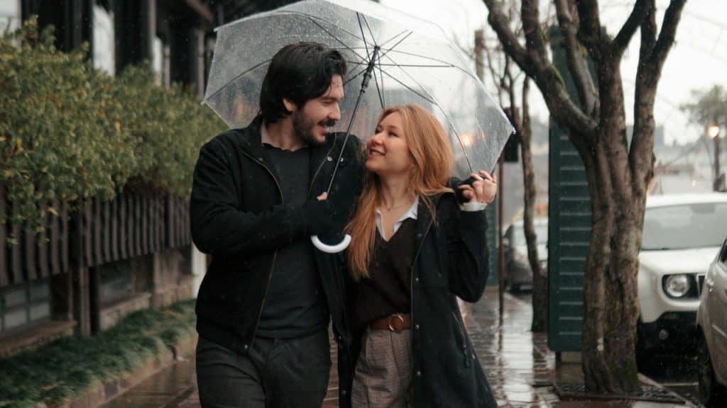 A couple walking under an umbrella on a rainy street.