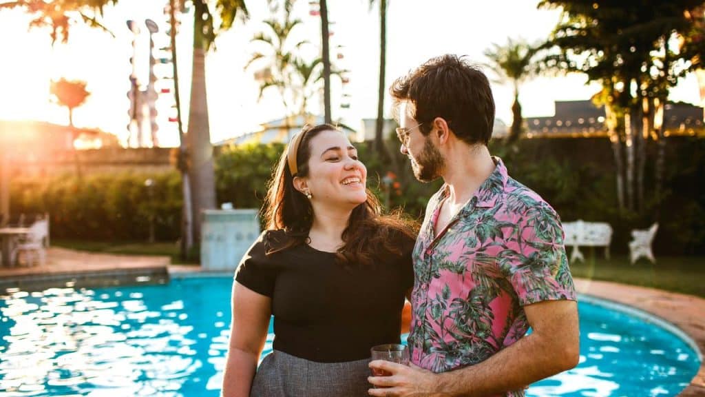 A couple smiling at each other while standing by a pool.