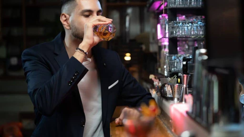 Man holding too many drinks at a bar
