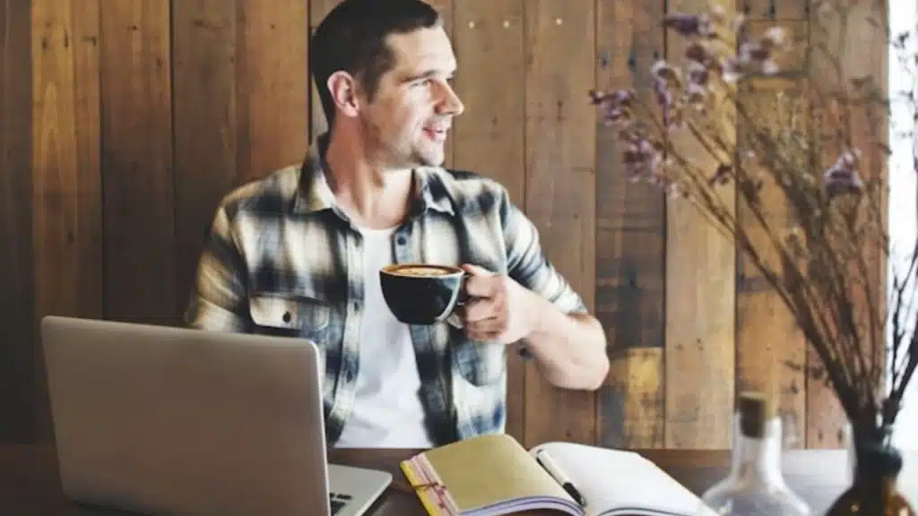 A thoughtful man sitting in a café, looking distant while holding a coffee mug