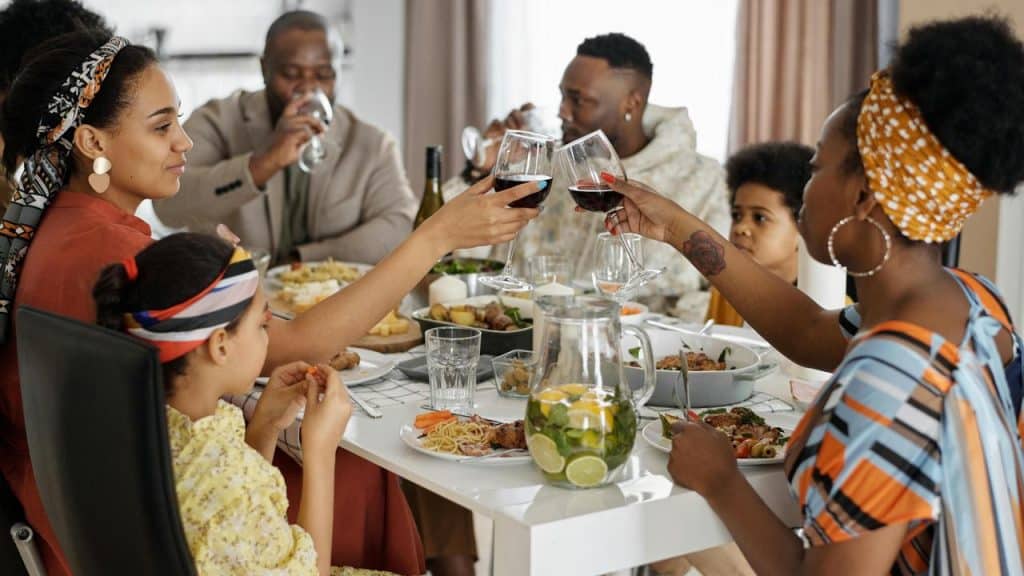 A family gathered around a table enjoying a meal and toasting with wine glasses.