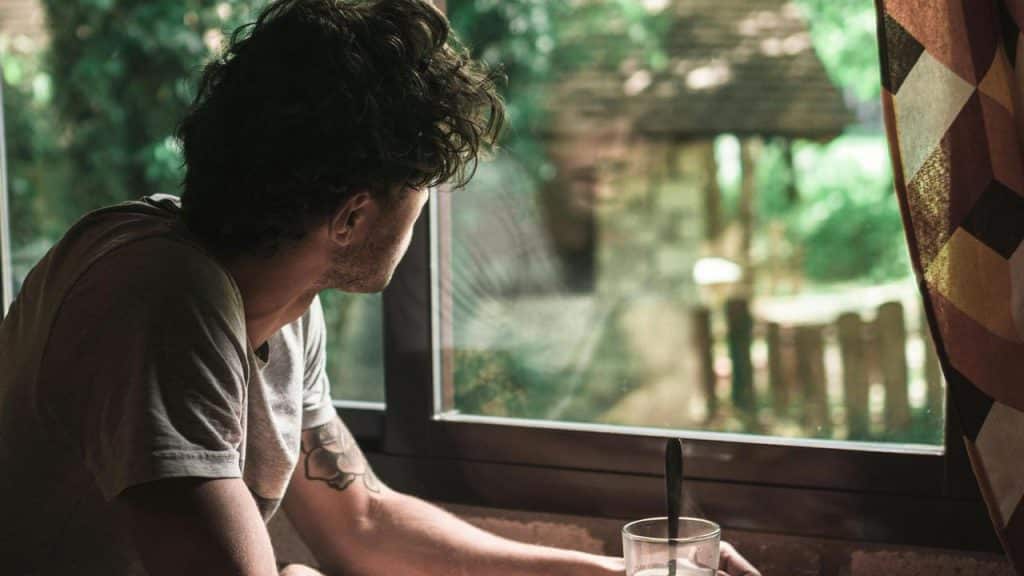 A man sitting by a window and looking outside thoughtfully.