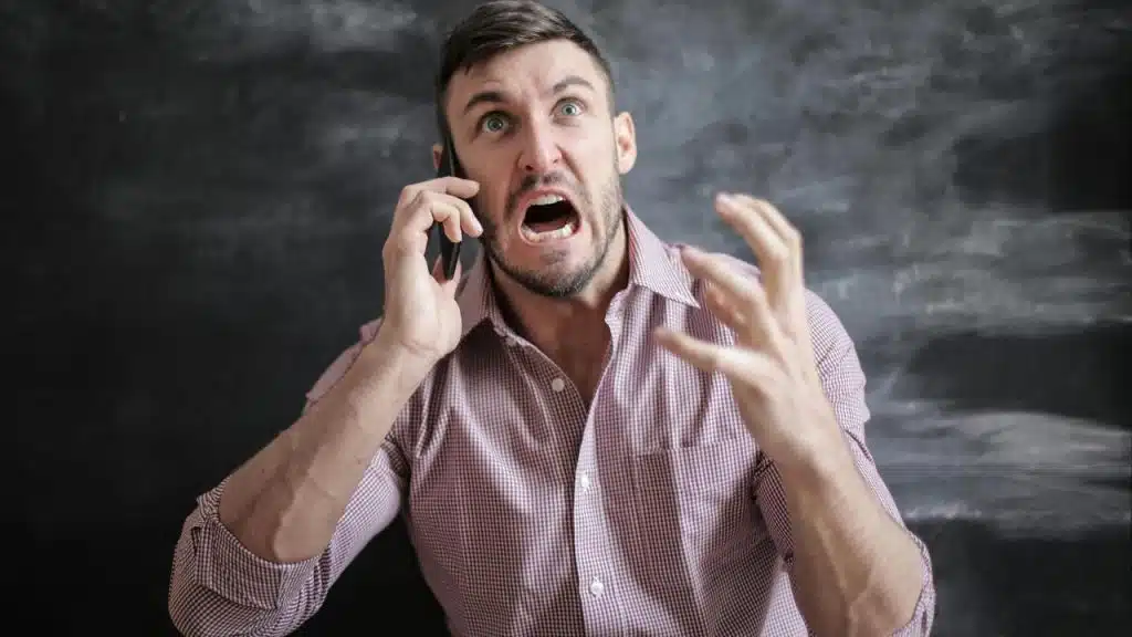 A man shouting angrily while talking on a phone.