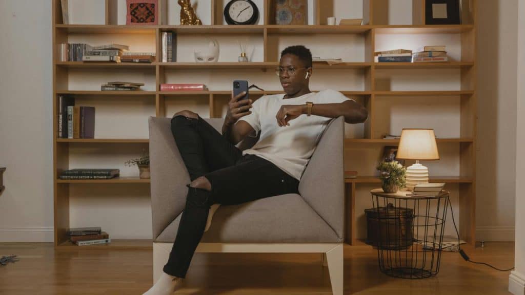 A person sitting in a chair and looking at their phone.