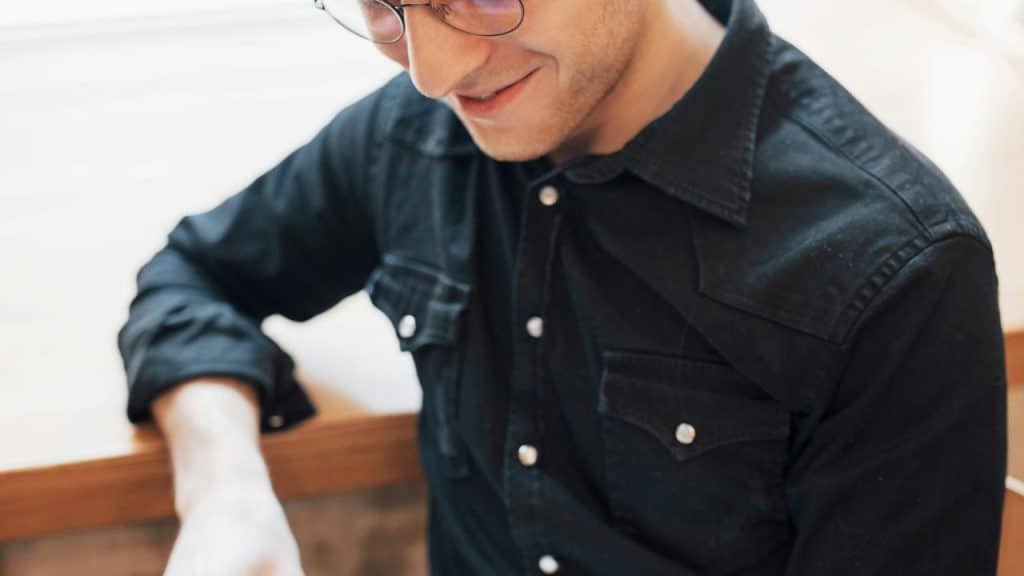 A person in a black shirt smiling while looking down.