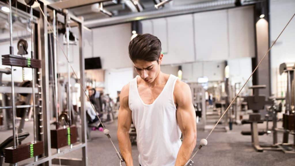 A young man working out in a gym on a cable machine.