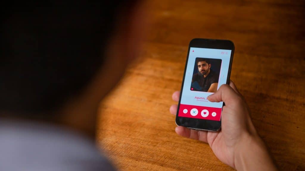 Over-the-shoulder view of a person holding a smartphone, viewing a dating app profile.