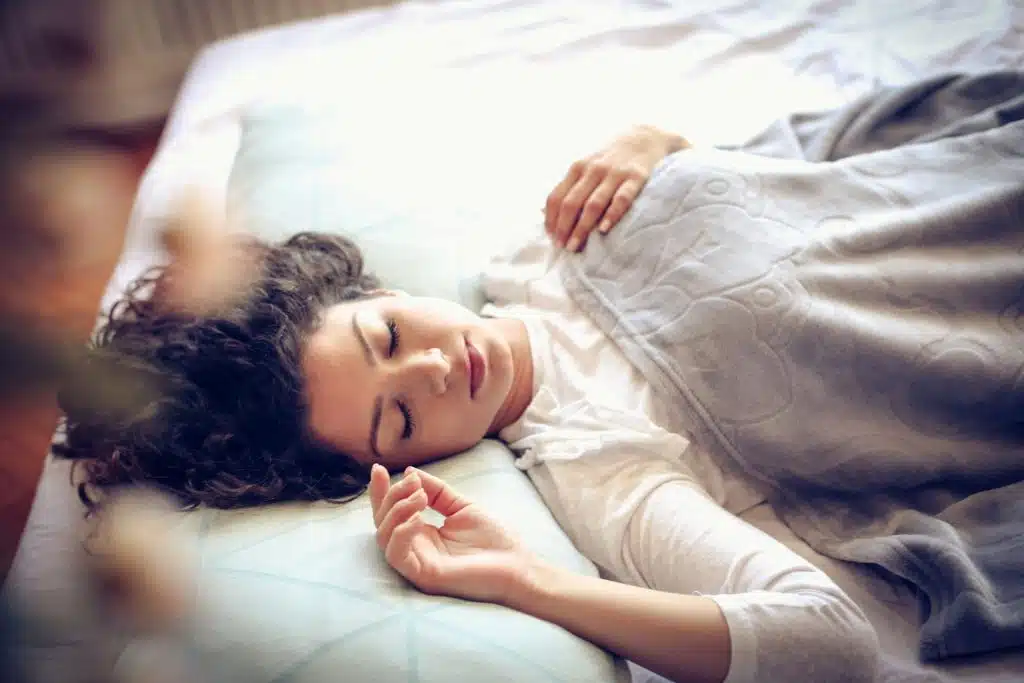 The woman is peacefully sleeping in the bed with her blanket.