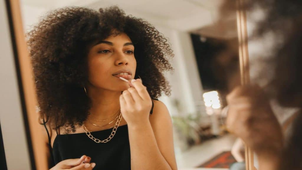 A woman applying lipstick in front of the mirror