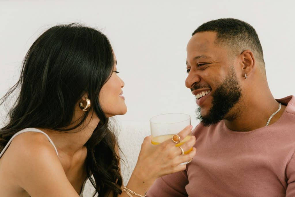 The woman is holding her drink while spending time with the man.